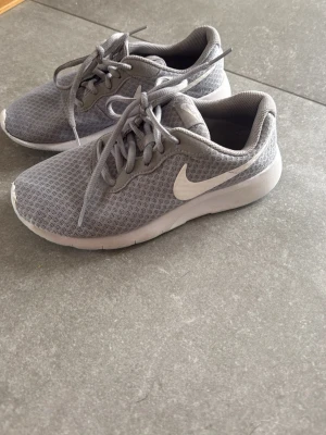 Grå Nike sneakers med vit sula - Snygga grå sneakers från Nike med vit sula som har färgats lite blå under eftersom att de är använda fåtal gånger i en idrottshall. . 