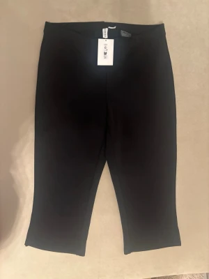 Svarta croppade leggings - Snygga svarta leggings med croppad längd och hög midja. Tillverkade i ett stretchigt material som sitter bekvämt och följsamt. Perfekta att matcha med oversized tröjor eller hoodies för en chill look.