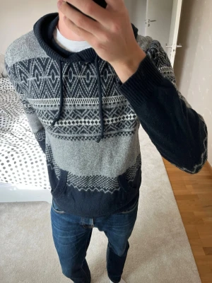 Mörkblå och grå stickad hoodie från Hollister  - Säljer en väldigt snygg vintage stickad hoodie från Hollister i ett otroligt skönt material! Tröjan har inga defekter! 😊✌🏼——————————————————————————                                  📐| Storlek: M                                                             👖| Märke: Hollister                                                🔎| Skick: MYCKET FINT!                                                     ✍🏻| Skriv om du har några frågor