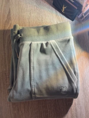 Ljusgröna Juicy Couture - Säljer ett par grå mjukisbyxor i velour från Juicy Couture. Byxorna har dragsko i midjan med metalländar, snedställda fickor och en liten broderad logga framtill. Perfekta för en chill och avslappnad stil. Precis som nya, köpta för 1200kr 🥰