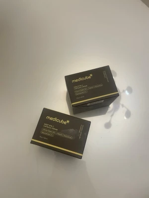 Medicube Deep Vita Cream foundation - Medicube Deep Vita Cream Capsule Foundation i mörkgrå förpackning med gulddetaljer. Innehåller vitaminer och kapselteknologi för en jämn och återfuktad bas. Kommer i praktisk box på 50 g. Perfekt för dig som vill ha en naturlig och fräsch look.