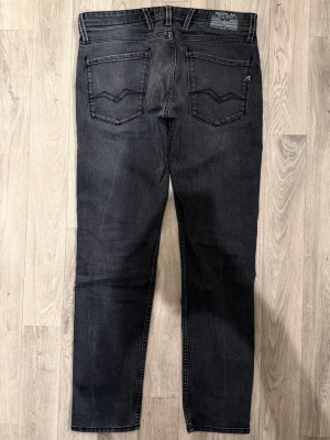 Replay Anbass Jeans Mörkgrå W33/L32 - Slim Fit - Replay Anbass mörkgrå jeans med slim fit passform som sitter snyggt och bekvämt och funkar till allt, storlek W33/L32, midja 45 cm, ytterbenslängd 105 cm, benöppning 17 cm, modellen är 185cm & väger 65kg, i fint skick.