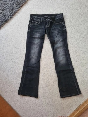 Mörkblå bootcut jeans - Snygga mörkblå bootcut jeans med diskreta slitningar framtill och bakfickor med dekorativa sömmar.Ny pris 800kr