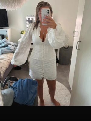 Vit kort klänning med spetsdetaljer - (Bilderna är från min vinted) Jättefin vit klänning, använd 1 gång därav ingen prislapp kvar. Spets/mönster klänning. Med knappar hela vägen och dragkedja i ryggen.