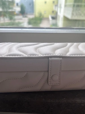 Vitt smyckeskrin från Primark - Snyggt vitt smyckeskrin från Primark med quiltat mönster och knappstängning. Insidan har spegel och fack för ringar och småsaker. Perfekt för att organisera dina favoritsmycken på ett stilrent sätt.