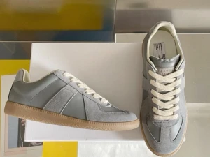Grå maison margiela sneakers med mockadetaljer - Snygga Maison margiela sneakers i grått med både mocka och släta paneler, vita snören och klassisk gummisula i brunt. Skorna har en stilren och tidlös design som passar till det mesta. Låg modell med bekväm passform och neutrala färger. Gats