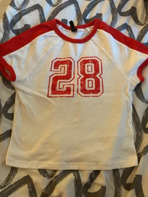 vit och röd t-shirt - snygg vit t-shirt med röda ärmar och krage samt trycket '28' i rött framtill. storleken är s men den är liiite tajt så skulle mer säga xs