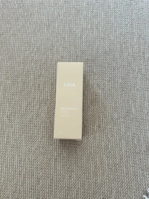 CAIA The Essential oil - Säljer en CAIA The Essential oil i en stilren beige förpackning. Produkten är en ansiktsolja och kommer i en rektangulär kartong med minimalistisk design. Perfekt för dig som vill boosta din hudvårdsrutin.Oöppnad och oanvänd, förpackningen är plomberad