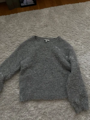 Grå fluffig stickad tröja  - Mysig grå stickad tröja från Ayluna med fluffig och mjuk känsla. Tröjan har rund halsringning och långa ärmar, perfekt för kyliga dagar. Passar dig som gillar en enkel men trendig look.