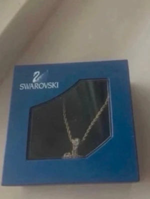 Swarovski halsband med hjärthänge(barn) - Guldpleterat halsband från Swarovski med ett hjärtformat hänge dekorerat med gnistrande stenar. Kedjan är tvinnad och smycket levereras i original blå ask. Perfekt accessoar för att lyfta din stil.saknar 4stenar å lite hår sitter fast i back vid spännet 