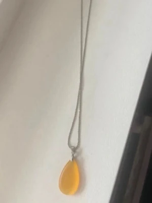 Halsband med droppformad gul hängberlock - Snyggt halsband med en tunn silverfärgad kedja och en droppformad, gul hängberlock i glas eller akryl. Perfekt för dig som vill ha en färgklick till din outfit. Enkel och stilren design som sticker ut.