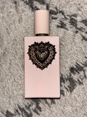 Rosa parfymflaska med hjärtdekor - Säljer en superfin parfym i en ljusrosa, rektangulär flaska med ett detaljerat guldfärgat hjärta på framsidan. Flaskan har en matchande rosa kork och känns riktigt lyxig och elegant. Perfekt som present eller till dig själv! bara testad, köpt för runt 2000kr. kommer med förpackningen, kom gärna med bud och frågor ❤️❤️