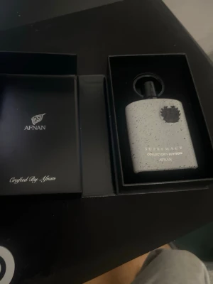 Afnan Supremacy Collector's Edition parfym - Unik parfym från Afnan, Supremacy Collector's Edition. Flaskan är vit med svarta stänk och har en modern, fyrkantig form. Levereras i exklusiv svart presentförpackning med elegant design. Perfekt för dig som gillar stilrena och trendiga dofter.