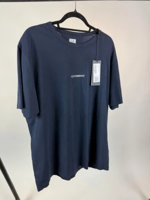 Mörkblå t-shirt från C.P. Company - Snygg mörkblå t-shirt från C.P. Company med diskret logga på bröstet. Klassisk rund hals och korta ärmar. Tillverkad i mjuk bomull som känns skön mot huden. Perfekt för en clean och stilren look.
