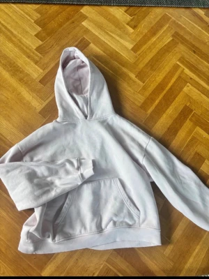 Ljusrosa hoodie - Mysig ljusrosa hoodie med huva och stor magficka framtill. Hoodien har ribbade muddar vid ärmslut och nederkant samt mjukt fleecefoder på insidan. Perfekt för en avslappnad och chill stil. 