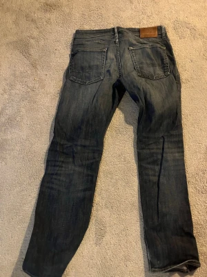 Mörkblå raka jeans - Säljer ett par mörkblå jeans med raka ben och klassisk femficksdesign. Jeansen har en läderpatch bak i midjan och är tillverkade i denim. Perfekta för en avslappnad och stilren look. Längden och waist sizen är 28:32