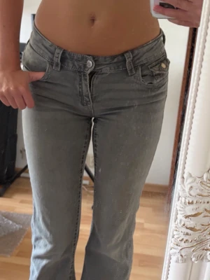 Low waist bootcut jeans med broderade fickor - Säljer ett par gråa lågmidjade bootcut jeans med snygga broderade detaljer på bakfickorna💕köpta på vinted men säljer då de inte kommit till användning 