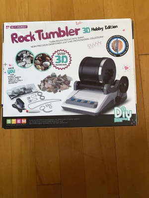 Rock Tumbler 3D Hobby Edition - Rock Tumbler 3D Hobby Edition är ett DIY-kit för att polera och slipa stenar till glänsande ädelstenar. Setet innehåller en svart och vit maskin, stenar, tillbehör och strömkabel. Perfekt för dig som gillar att skapa och experimentera med naturmaterial.