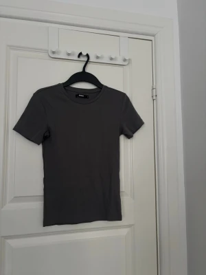 Grå t-shirt från BikBok - T-shirten har korta ärmar, rund halsringning och är gjord i bomull. 