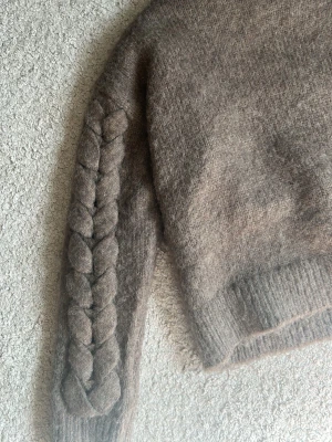 Beige stickad tröja med fläta - Mysig beige stickad tröja med rund hals den är ganska kort 