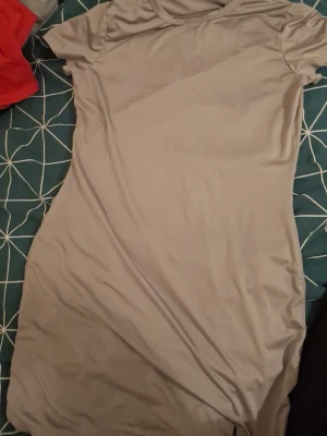 Ljusgrå kortärmad klänning - En enkel och stilren ljusgrå klänning med korta ärmar och rund hals. Klänningen har en rak passform och är tillverkad i ett mjukt och stretchigt material, perfekt för en avslappnad look. Går även och ha som ett natt linne.