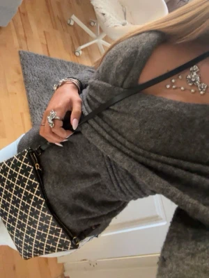 Grå omlottopp med v-ringning - Snygg grå omlottopp med djup v-ringning och långa ärmar. Toppen har en figurnära passform och är tillverkad i mjukt stickat material, perfekt för en trendig vardagslook.