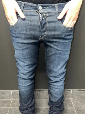 Replay Jeans  - Snygga mörkblå slim fit jeans med kontrastsömmar och klassiska fem fickor. Jeansen har en något tvättad look och raka ben som smalnar av. Perfekta för dig som gillar en modern och stilren stil.