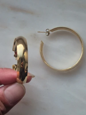 Vintage guldpläterade örhängen,  60-tal - Säljer ett par vimtage örhängen guldpläterade. De har en klassisk, slät och glansig yta som ger en stilren look. Perfekta för dig som gillar statement-smycken och vill addera lite extra bling till din outfit. OANVÄNDA