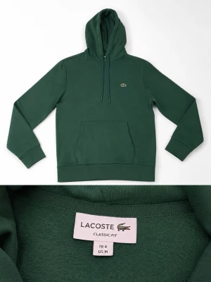 Grön hoodie från Lacoste - Mörkgrön hoodie från Lacoste i klassisk passform. Tröjan har huva med dragsko, magficka och den ikoniska krokodilloggan broderad på bröstet. Tillverkad i mjukt material som känns skönt mot huden. Perfekt för en avslappnad och stilren look.