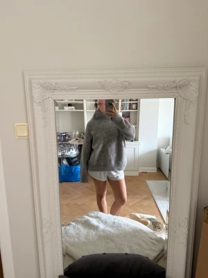 Grå stickad polotröja - Mysig grå stickad polotröja med avslappnad passform och ribbade muddar vid ärmslut och nederkant. Tröjan har hög krage och är perfekt för kyliga dagar. 