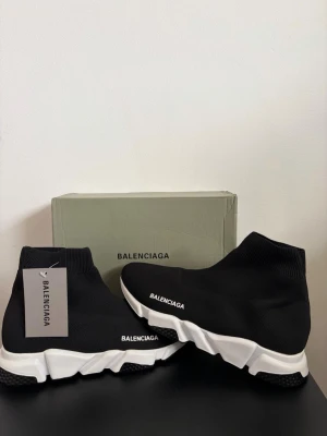  sneakers svart - Säljer ett par svartasneakers med vit chunky sula och stickad ovandel i textil. Skorna har en strumpliknande passform och logga på sidan. Perfekta för dig som gillar en modern och sportig look.