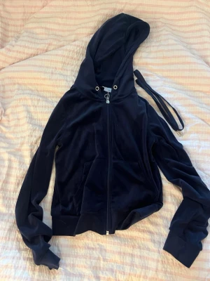 Mörkblå velour hoodie med dragkedja - Snygg mörkblå hoodie i mjuk velour med dragkedja framtill och stor huva. Modellen är något croppad och har muddar vid ärmslut och midja samt en två fickor på magen. Perfekt för en chill och trendig look.