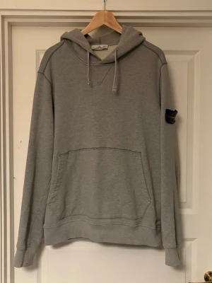 Stone Island Hoodie - Äkta hoodie från Stone Island, har täckt Certilogo QR-koden eftersom folk kan använda den för att lura andra, men vill ni se den så är ser bara att skicka ett PM så får ni en bild av den! den är stolek L, gråfärgad och är inte så himla använd! 