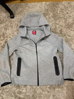 Grå Nike hoodie med dragkedja - Nike tech i storlek xl barn 158/170
