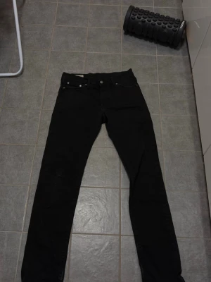 Svarta Levis 511 - Säljer ett par svarta jeans med rak passform och klassisk femficksdesign. Jeansen har bälteshällor och knappgylf. Passar perfekt till en avslappnad och stilren look. Finns en liten fläck på ena knät 
