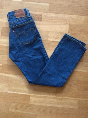 Levi's 501 blå raka jeans - Klassiska blå Levi's 501 jeans med rak passform och fem fickor. Jeansen har den ikoniska röda Levi's-lappen på bakfickan och läderpatch i midjan. 