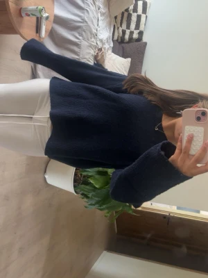 Mörkblå stickad tröja med vida ärmar - Mysig mörkblå stickad tröja med avslappnad passform och vida ärmar. Tröjan har rund halsringning och är tillverkad i ett mjukt material som passar perfekt till jeans eller kjol. Enkel och stilren design som funkar året runt.