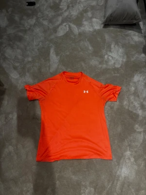 Under armour t shirt - Använd MAX 2 ggr, riktigt snygg och fräsch, den e lite mer rosa aktig i verkligheten alltså inte så knall orange 