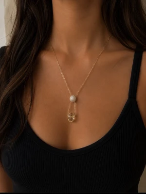 Guldhalsband med kristall detaljer - Snyggt halsband i guld med tunn kedja, dekorerat med en rund pärlliknande detalj och en droppformad klar kristall. Perfekt för dig som gillar stilrena och eleganta accessoarer med en unik twist.