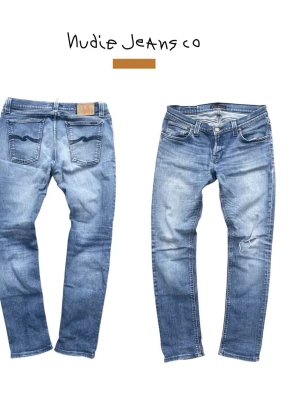 Blå jeans från Nudie Jeans Co - Snygga blå jeans från Nudie Jeans Co i klassisk femficksmodell. Jeansen har en tvättad look med slitningar och en liten reva på ena benet. Broderade bakfickor och normal passform. Tillverkade i denim av bomull.