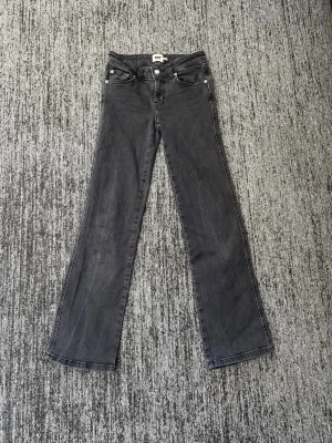 Svarta bootcut jeans med silverknappar - Snygga svarta bootcut jeans med fem fickor och silverfärgade knappar. Jeansen har en klassisk passform med lätt utsvängda ben och normal midja. Perfekta till sneakers eller boots för en avslappnad look.