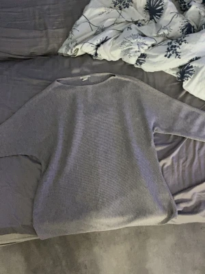 Ljusgrå/beige stickad tröja i basic stil - En enkel och stilren ljusgrå stickad tröja i basic modell. Tröjan har rund halsringning och är tillverkad i ett mjukt, tunt stickat material. Perfekt för hösten å våren. Korta armar till armbågen. Bekväm om man bara vill ha nått fint men skönt på sig.