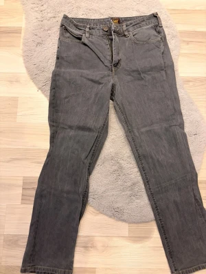 Grå raka jeans från Lee - Snygga grå jeans från Lee med klassisk rak passform. Jeansen har normal midja och är gjorda i slitstarkt denimtyg. Perfekta för dig som gillar en enkel och tidlös stil.