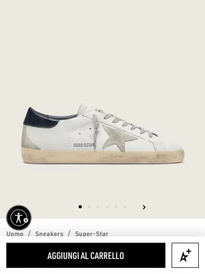 Golden Goose Super-Star vita sneakers - Golden Goose Super-Star sneakers i vitt läder med grå stjärndetalj på sidan, grå skosnören och blått hälparti. Sulan har en vintage-look med smutsad finish. Klassisk låg modell med ikonisk design och coola detaljer. Köpte för liten storlek men märkte det efter att jag hade använt de utomhus en gång. Kvitto kan visas vid intresse.