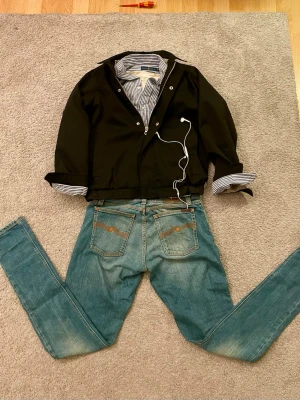 Jack & Jones svart Grisch jacka  - Snygg Grisch jacka  från Jack and Jones med rutigt innerfoder i beige och vitt. Jackan har klassisk krage, dragkedja och tryckknappar framtill samt två sidofickor. Storlek = 152cm men passar även 158cm. 