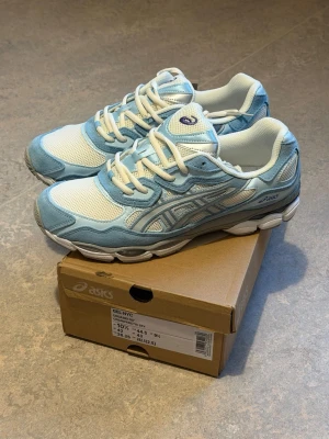 Asics GEL-NYC ljusblå sneakers - Säljer ett par fräscha Asics GEL-NYC sneakers i ljusblått och vitt. Skorna har mesh- och mockadetaljer, klassisk snörning och Ortholite-innersula för extra komfort. Perfekta för dig som vill ha en sportig och trendig look.