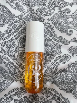 Sol de Janeiro 62 Parfym Mist - Fräsch och tropisk parfym mist från Sol de Janeiro, doft 62. Flaskan är genomskinlig med gul-orange vätska och har ett vitt lock. Perfekt att ha med i väskan för en snabb uppfräschning. 