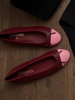 Chanel ballerinaskor vinröd/rosa - Snygga ballerinaskor från Chanel i vinrött läder med ljusrosa tåparti och klassisk rosett framtill. Skorna har rundad tå och den ikoniska Chanel-loggan broderad på tån. Perfekta för dig som vill ha en lyxig och trendig look.