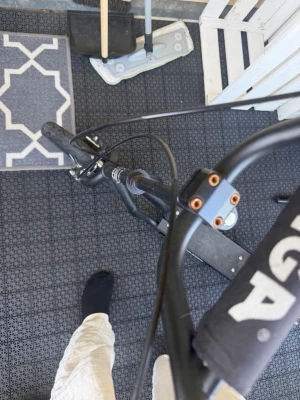 Svart sparkcykel med breda hjul - Säljer en svart sparkcykel med breda däck och robust ram. Styret har vadderad skyddskudde och flera bultar i orange. Passar perfekt för dig som vill cruisa runt eller ta dig fram snabbt i stan.
