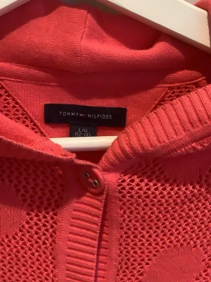 Rosa kofta med prickar Tommy Hilfiger - Snygg rosa/rosa kofta från Tommy Hilfiger med stora prickar och luva. Koftan har knäppning framtill, två fickor och ribbade muddar. Materialet är mjukt, stickat och luftigt vilket ger en cool och avslappnad look. Mysig och inte för varm❤️❤️ storlek 12 - 14år 